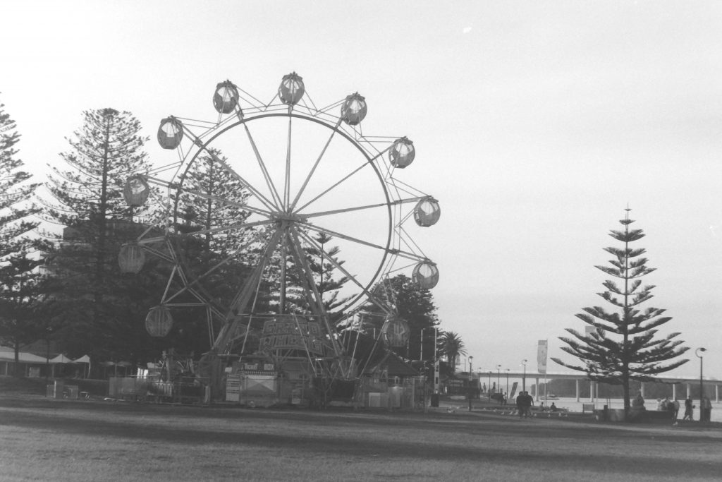 Black and white photograph of a ferris wheel alongside a walking path