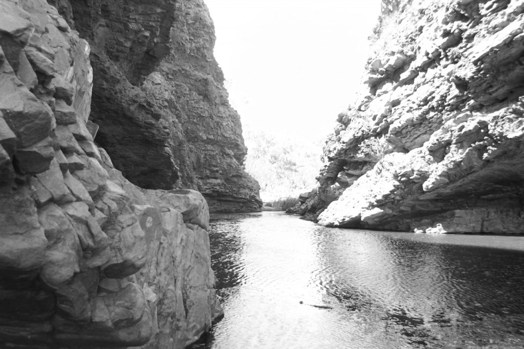 Black and white photograph of a stream running between two sides of a gorge