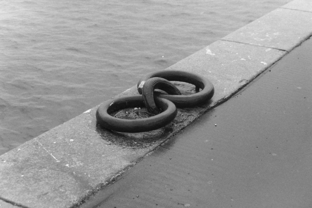 Black and white photograph of large mooring rings set into the stonework of a pier