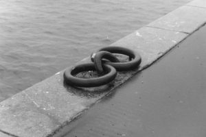 Black and white photograph of large mooring rings set into the stonework of a pier