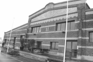 Black and white photograph of an old brick building with the number 11 on the front