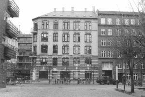 Black and white photograph of old stone apartment buildings around a paved square with bikes parked around the perimeter