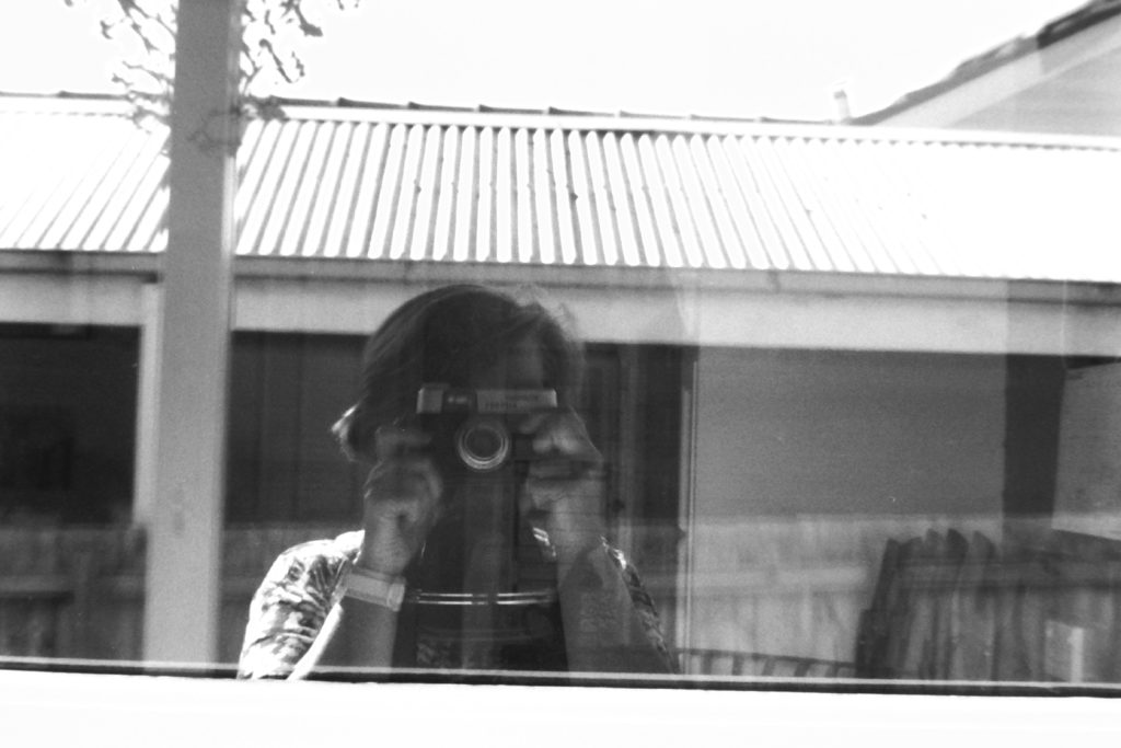 Black and white photograph of a photographer reflected in a window