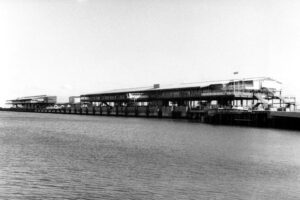 Black and white photo of a long pier extending over the bay