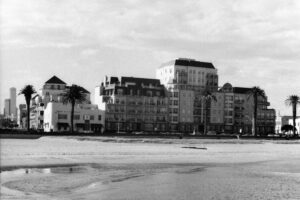 Black and white photo of apartment buildings and a beach in the foreground