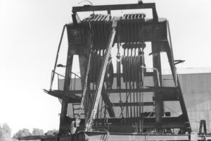 Black and white photograph of the pully system at the top of a dredging machine.