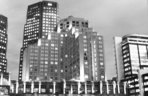 Black and white photo of office and apartment buildings at night with different lighting in each building.