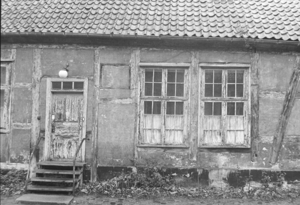 Black and white photo of a very run down wooden house.