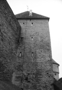 Black and white photo of a stone defensive wall with narrow rectangular windows.