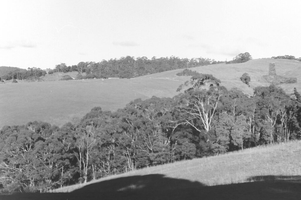 Black and white photograph of rolling hills of farmland and trees.