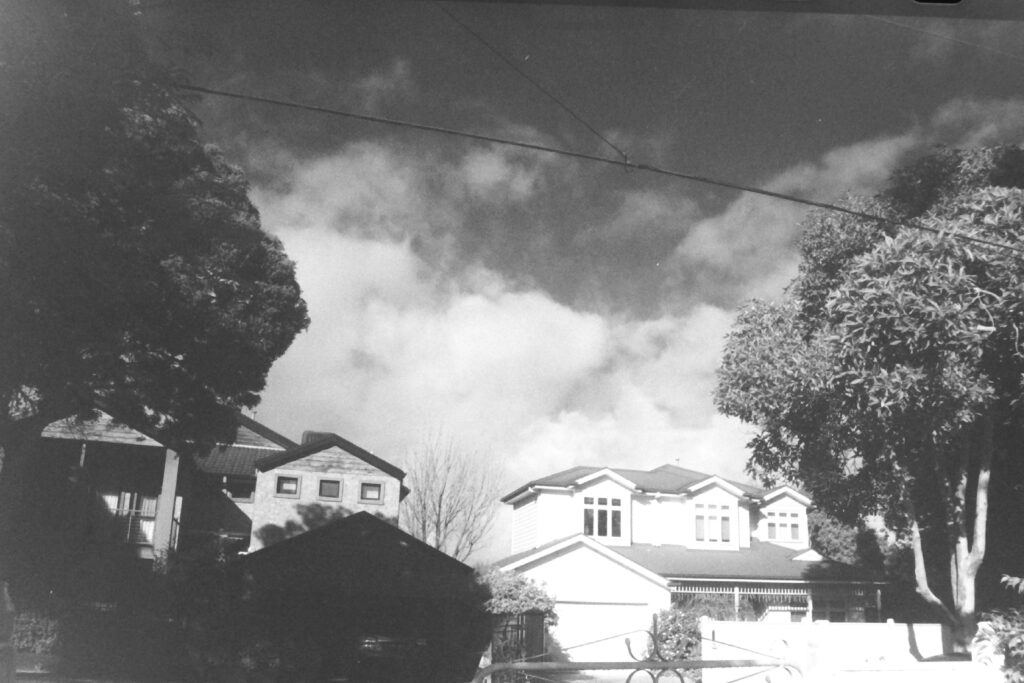 Black and white photo of two double storey homes with clouds looking behind.