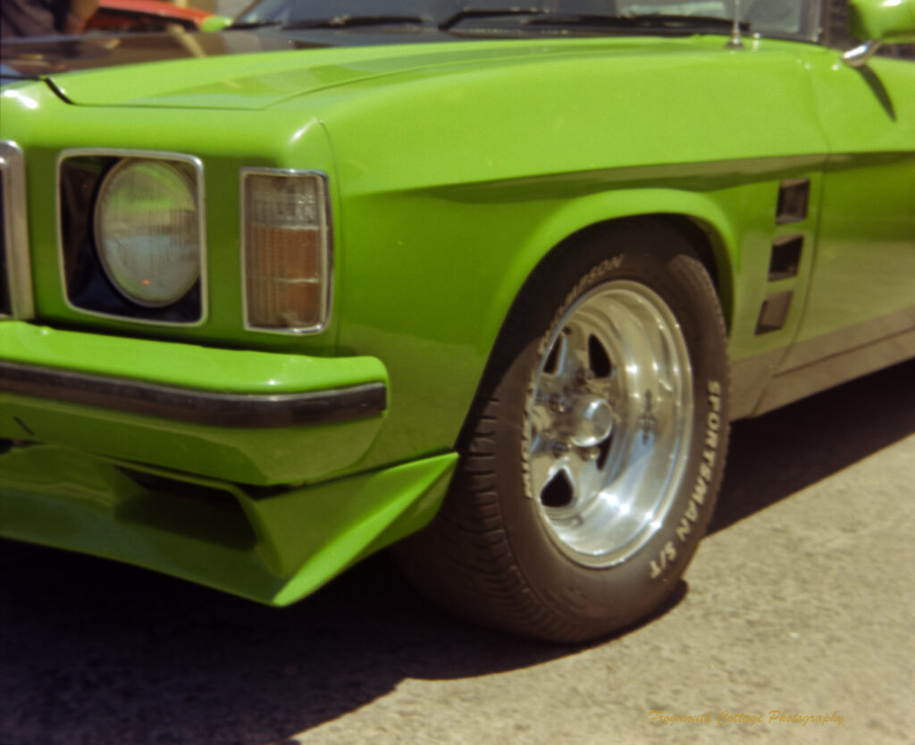 Close up photo of the front corner of a bright green car.