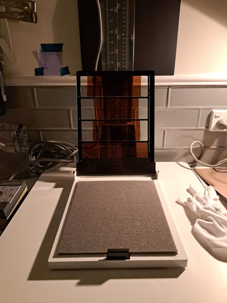Photograph of a Patterson Contact Printer with the top open and four strips of of 120 negatives inserted.